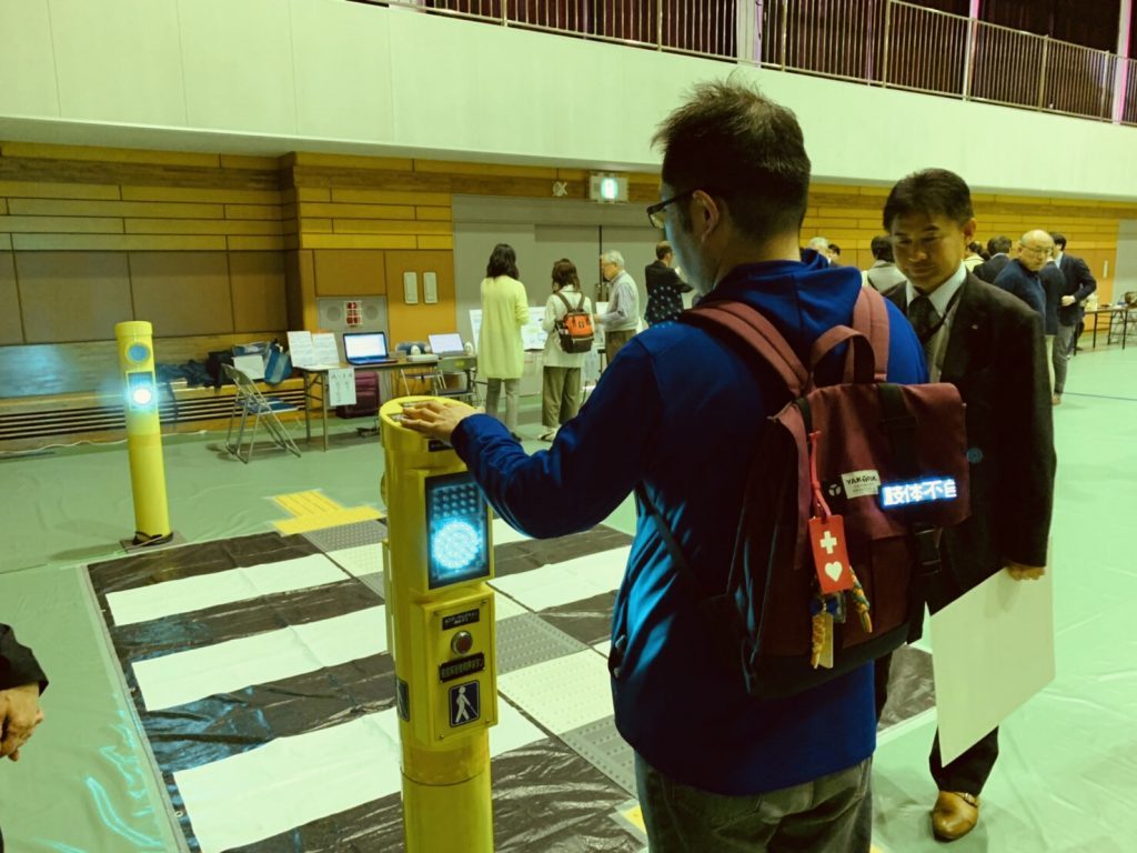 ポール型信号機に手を置く渡辺さん