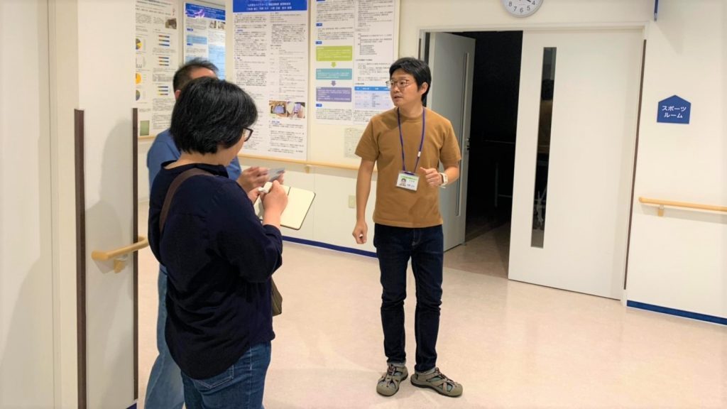 内野さんが施設の中を案内している画像。