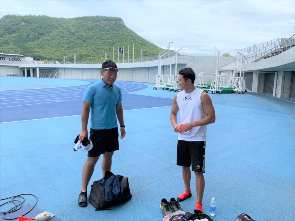 陸上競技場で田中さんと若生くんが談笑する画像