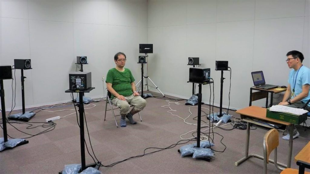 四方八方をスピーカーに囲まれている渡辺の画像