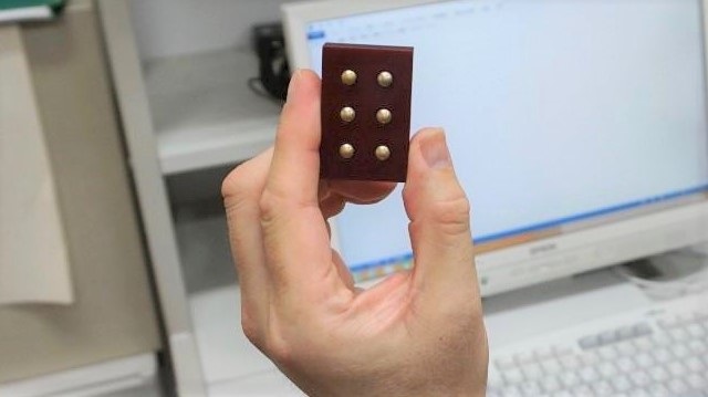 手のひらサイズの点字一文字分のブロックを手に持った画像