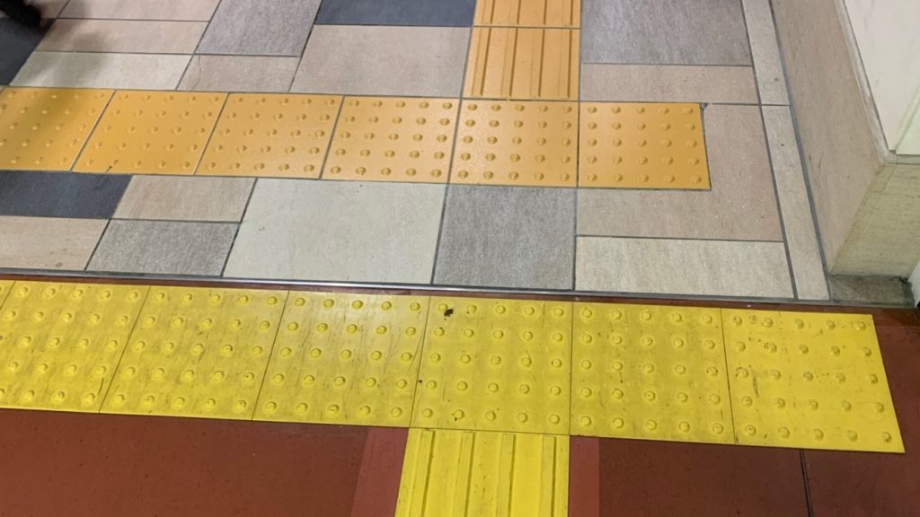 敷地の境目で、1度警告ブロックが轢かれて、点字ブロックが分断されている画像。