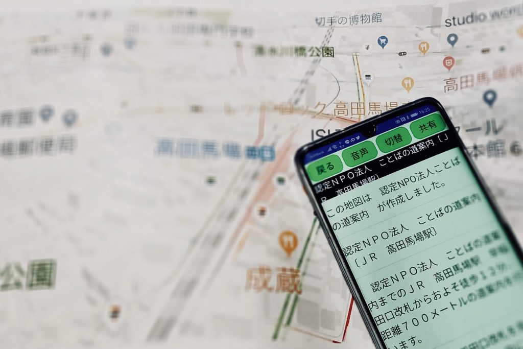 実際の地図の上に、ことばの道案内を開いたスマホを写している画像