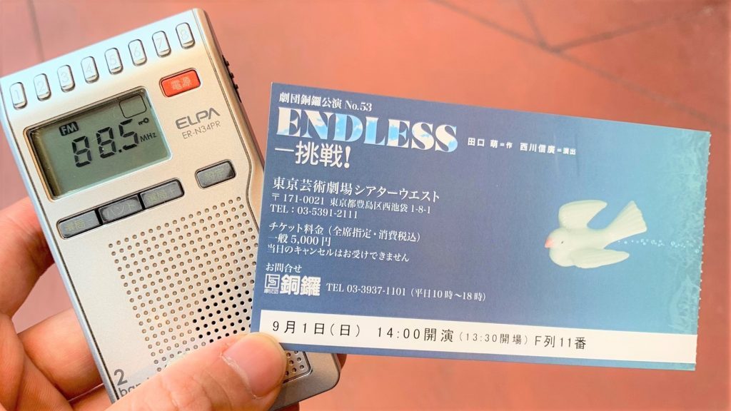 貸し出し用のポケットラジオとチケットを手に持っている画像。