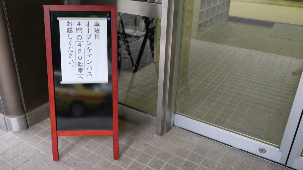 学校の入口に、オープンキャンパスの案内板が置かれている画像。