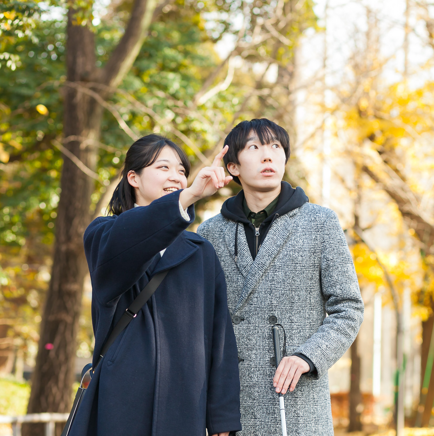 女性ヘルパーと男性の視覚に障害のあるかたが並んで歩いている様子