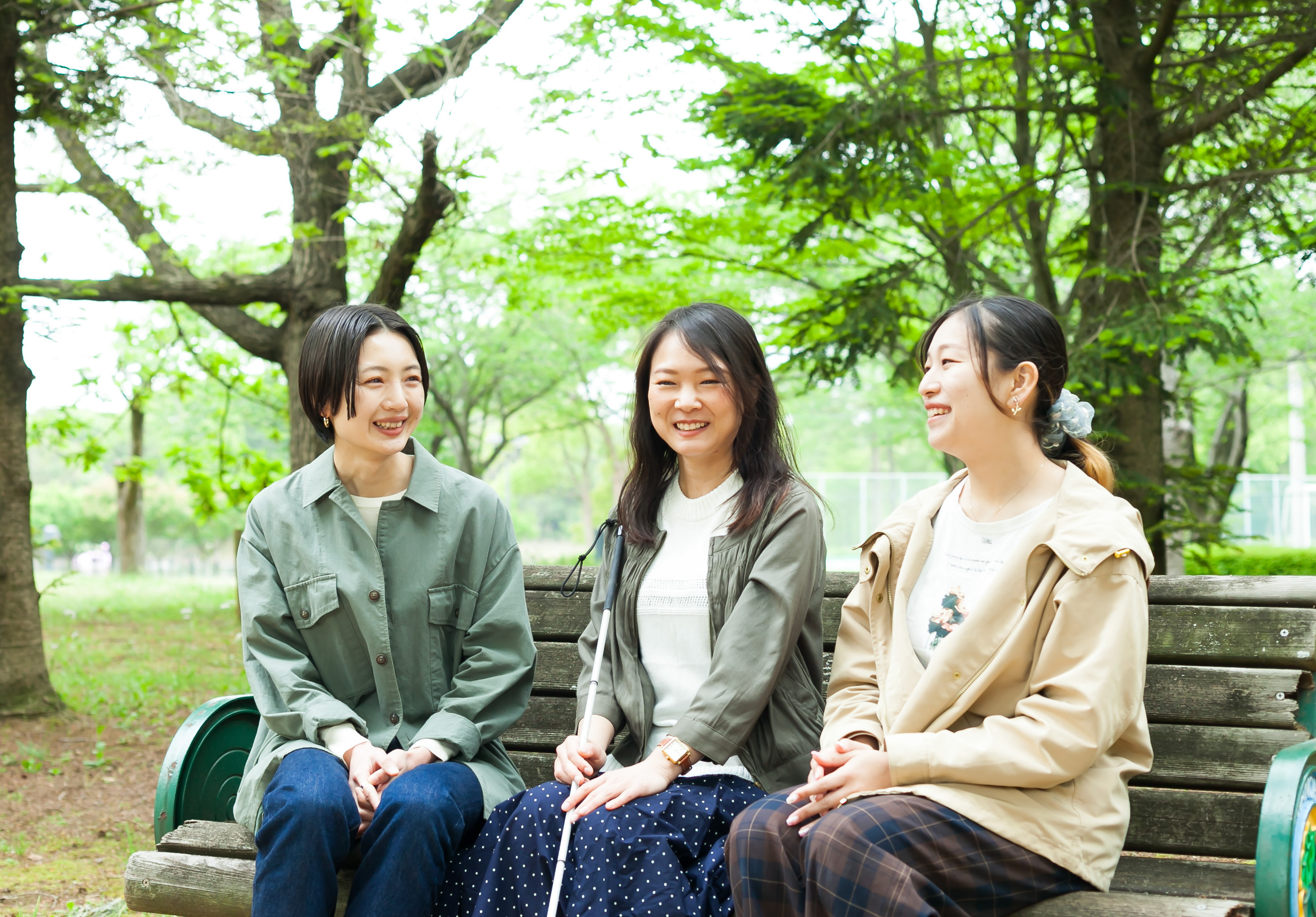 女性三人が屋外のベンチに座っている様子