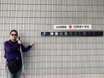 神奈川県ライトセンターの入り口にある看板を指さす渡辺敏之さん