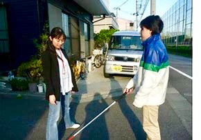 足を広げて訓練生に白杖のふり幅を伝える小倉さん