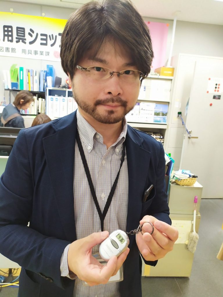 音声時計（キーホルダー型）を手に持つ澤村潤一郎さん