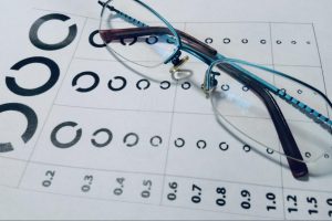 ランドルト環が書かれた視力検査表の上に眼鏡が置かれた画像