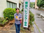東京ヘレン・ケラー協会の看板の横に立つ小倉さん