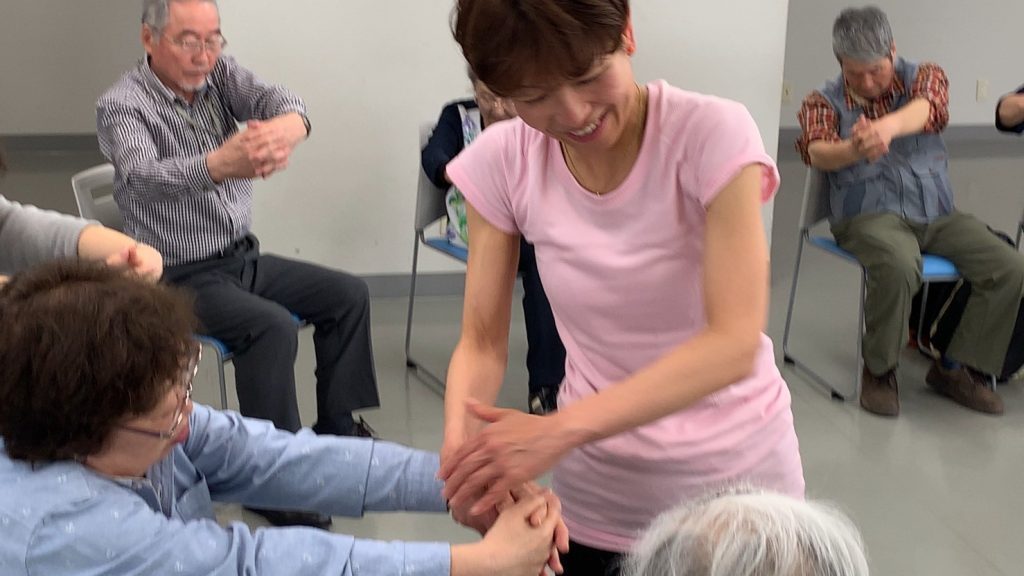 ヨガクラスで視覚障害者の身体に触れながら動きを伝える佐藤ゆみさん
