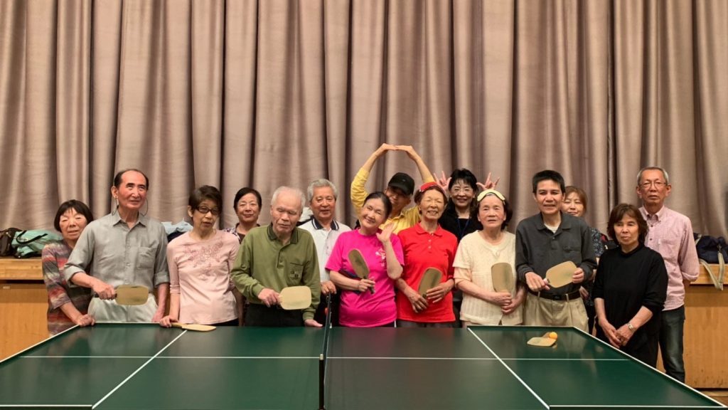 参加者全員が卓球台の後ろで記念撮影をしている画像