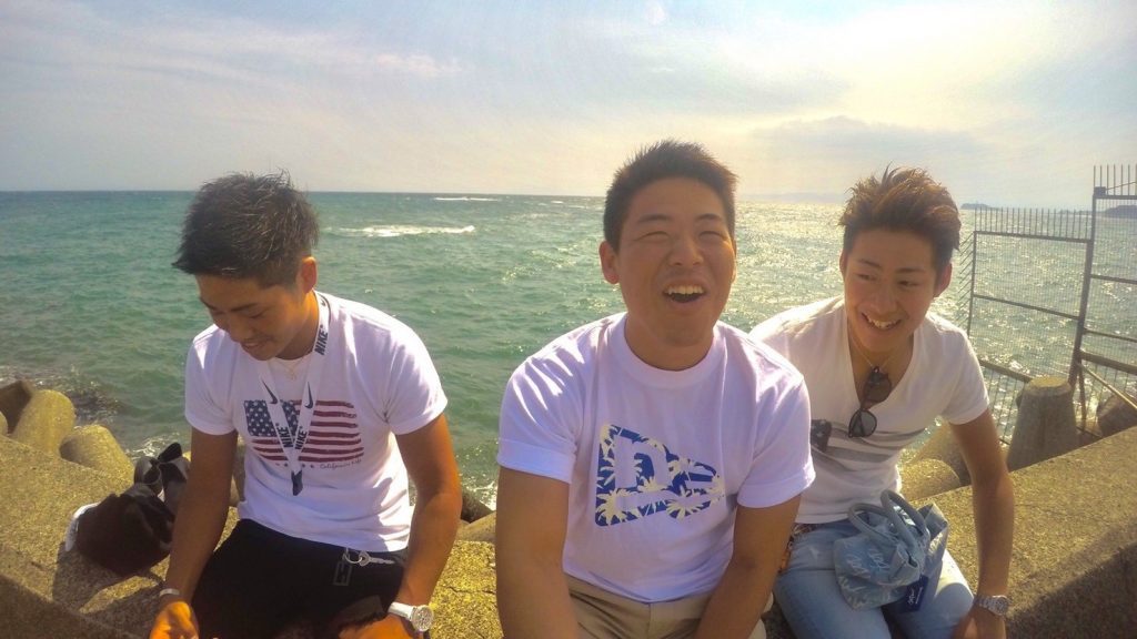 海を背に、友達ふたりと笑顔で写真に収まる山口さん