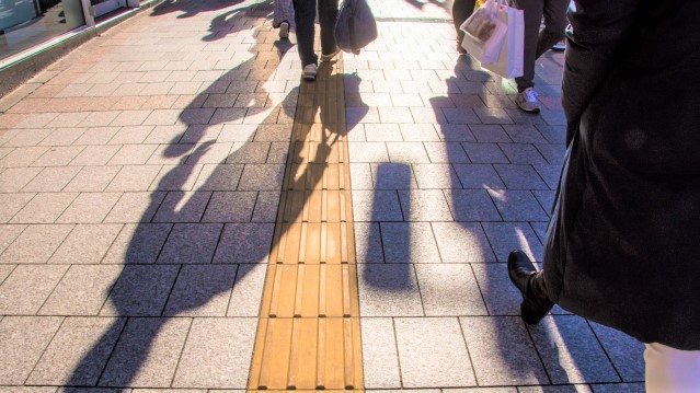 点字ブロッグが敷設されている道を歩く人影が写っている画像。