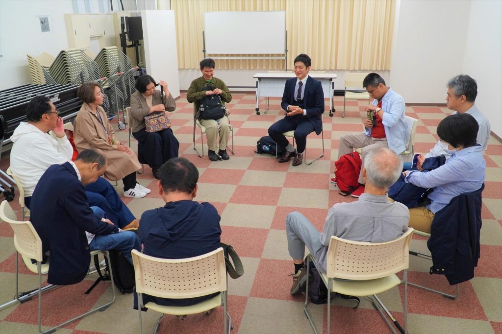 イベントの参加者が円形になって椅子に座り、話をしている画像。