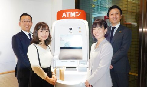 セブン銀行のATMの脇にスタッフ4名が笑顔で立っている画像。