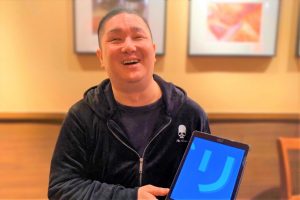 井上さんが笑顔でアイパッドを手にもっている画像。