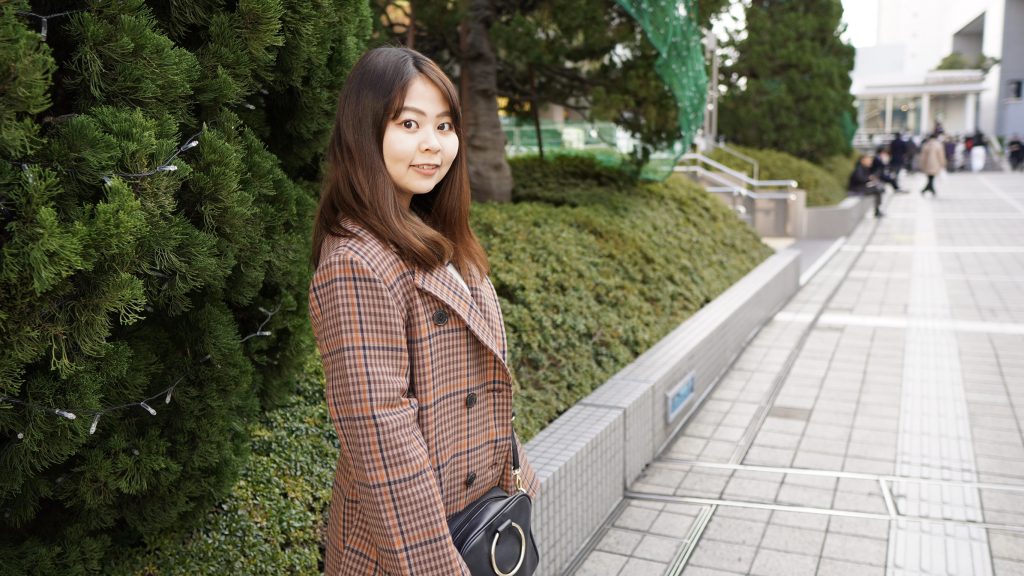 植木のそばで立っている櫻井さんの画像。