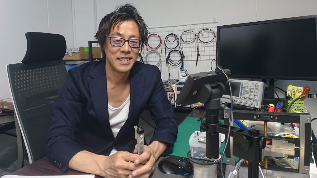 中村さんが笑顔でデスクに座っている画像。
