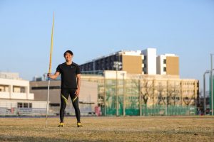 若生選手がやりをもって陸上競技場で立っている画像。