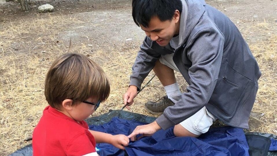 NPO法人の野外活動で、視覚障害児と一緒にテントを設営するクレメントさんの画像。