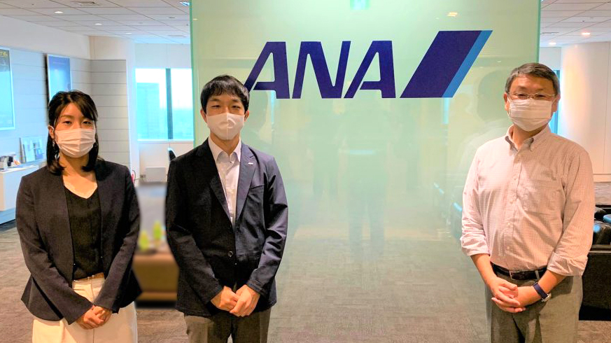 ANAのロゴの前で、大澤さん、黒岩さん、石井さんが立っている画像。