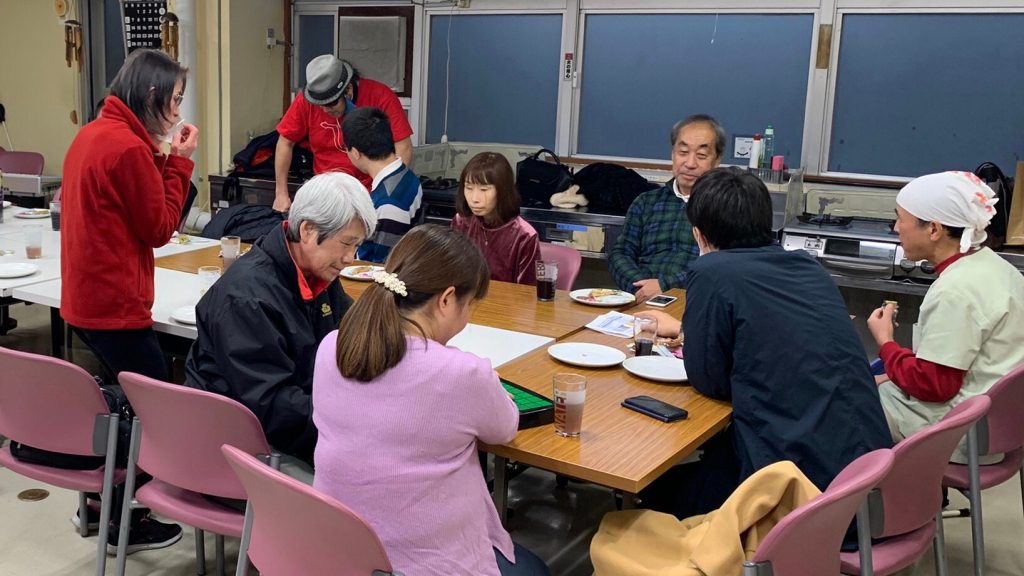 調理室で参加者がパンを食べながら談笑している画像。