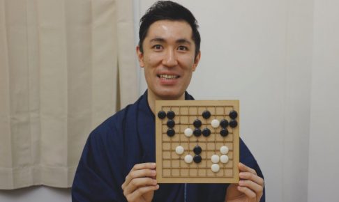 囲碁盤を笑顔で掲げる柿島さん