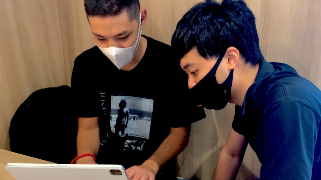 カフェで三輪と三好さんが一緒にiPadの画面を見て操作練習している画像