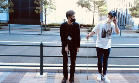 三好さんと三輪が歩道の脇でリラックスして立っている画像。