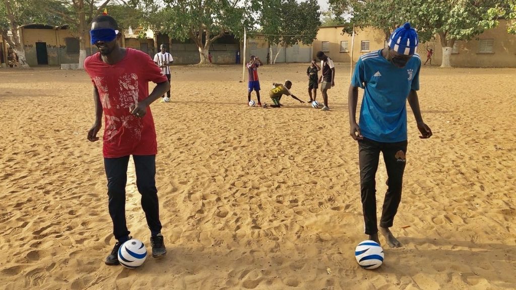 セネガルの砂地でアイマスクをしてブラインドサッカーをしている画像