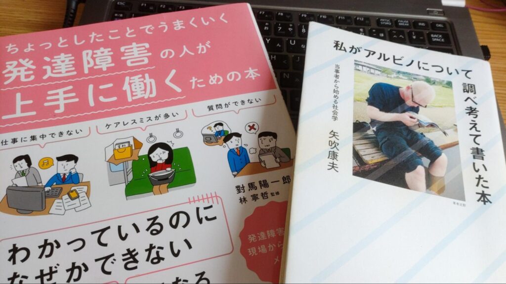 2冊の本。對馬 陽一郎著『ちょっとしたことでうまくいく 発達障害の人が上手に働くための本』と矢吹康夫著『私がアルビノについて調べ考えて書いた本』