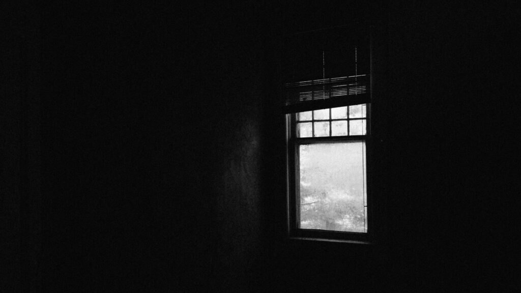 暗い部屋の中で、小さい窓から少しだけ明かりが入っているイメージ画像