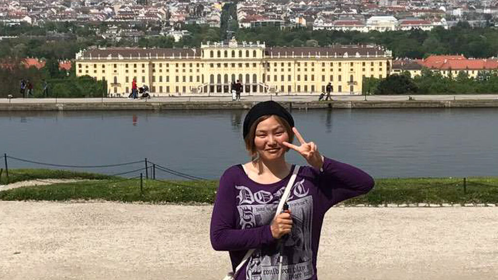 ウィーンのシェーンブルン宮殿を背景に、Vサインをする日向舞香さん。