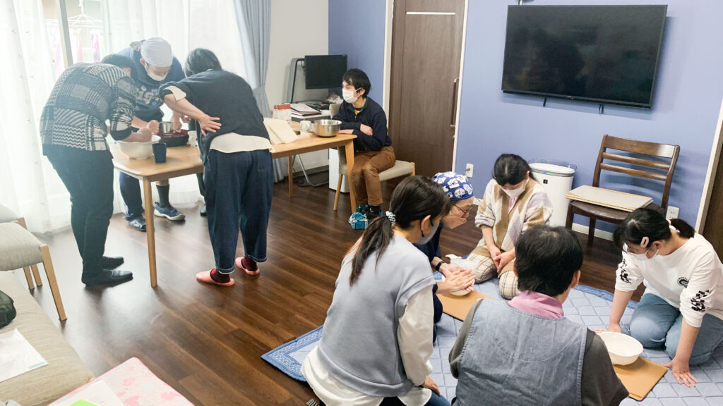 共有スペースで、そば打ち体験をししている写真。