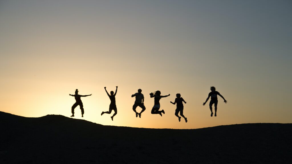 6人の人が楽しそうに飛び跳ねているシルエットの写真。