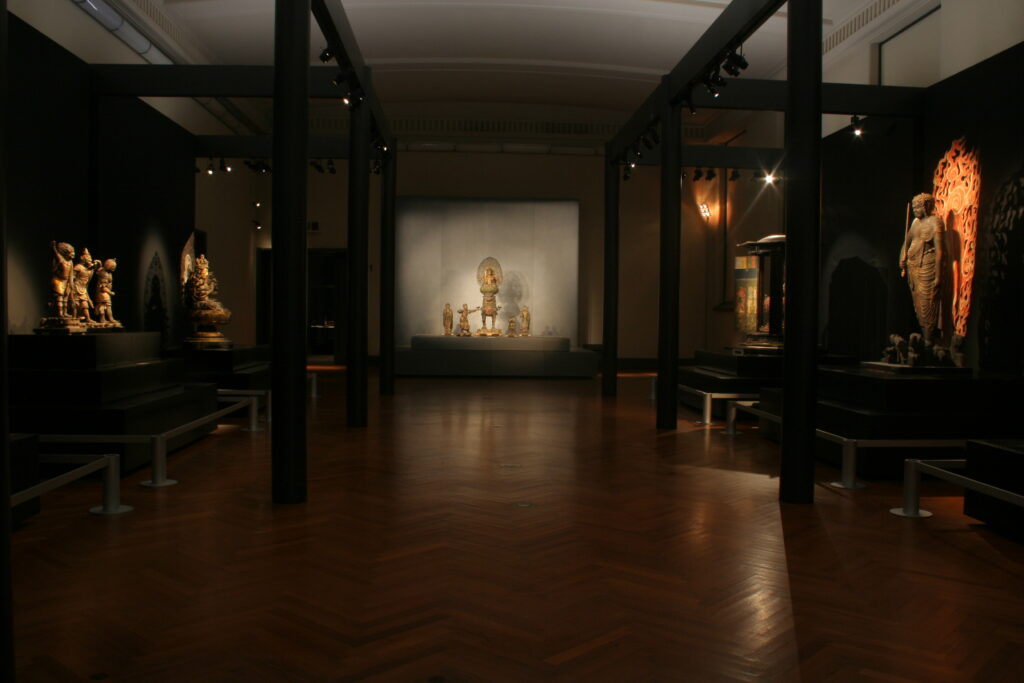 東京国立博物館の展示室。薄暗い中に仏像などが並んでいる。