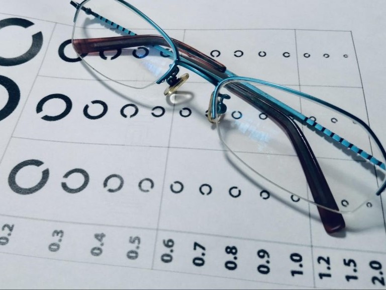 視力検査表の上にメガネが置かれている写真。