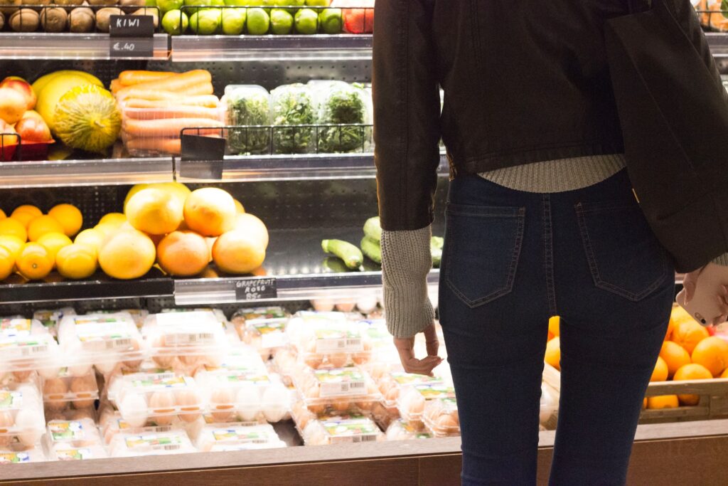 スーパーマーケットで棚に並んだ生鮮食品を探す女性