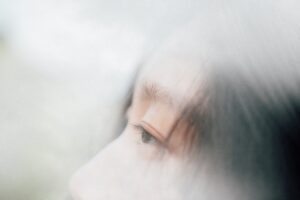 女性の横顔の目元のクローズアップ。やや伏し目がちで周囲にモヤがかかったようになっている。