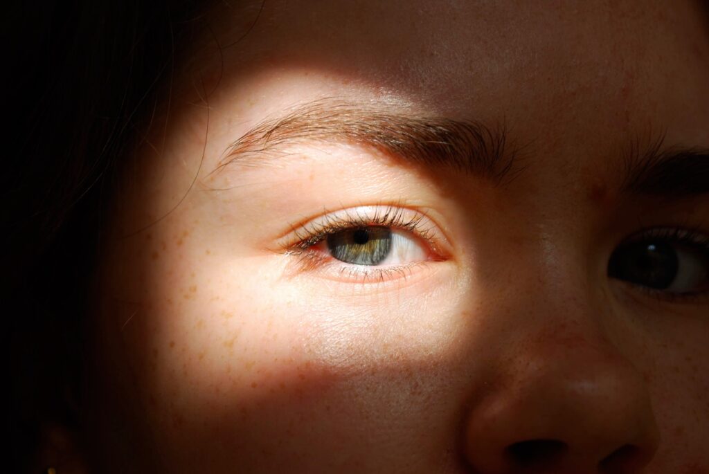 白人の女性か子どもの顔の右半分のアップ写真。瞳の部分だけに明るい光が当たっている。