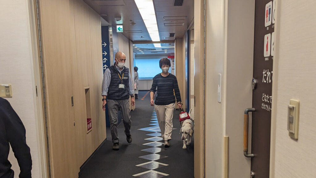 院内の廊下を盲導犬の誘導で歩く石原さん