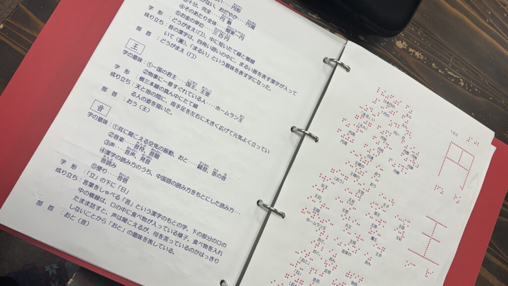 墨字の解説の隣のページに、点字、文字の形を点で表して触知できる見本などが記された教材。