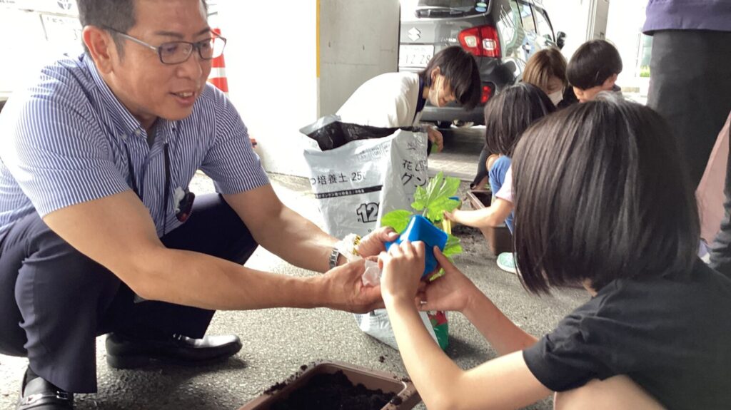 スタッフと子どもで植物の苗を植えている様子。