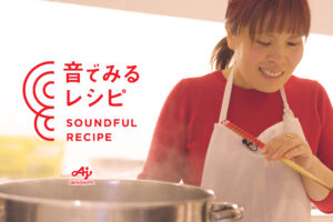 赤い服に白いエプロン姿の全盲のみきさんが菜箸を持っている。画像左側に「音でみるレシピ 「音でみるレシピ SOUNDFUL RECIPE」と赤い文字で書いてある。
