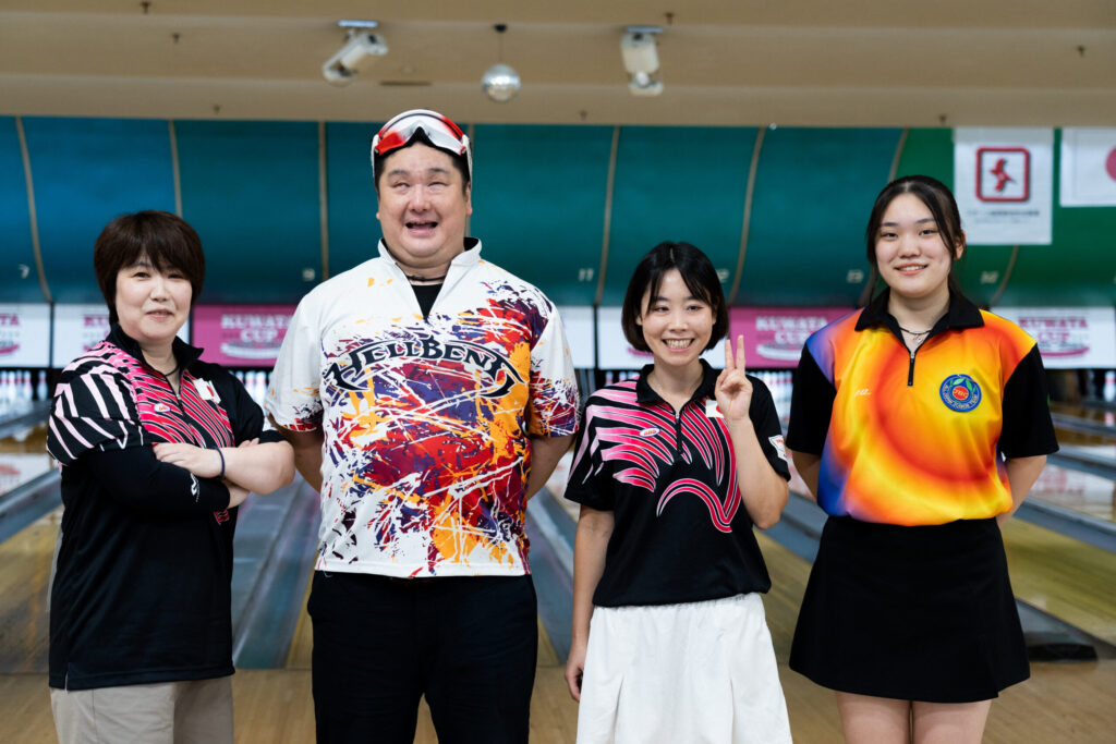 レーンを背景に撮影したチームの集合写真。向かって左から、尾形さん、井上さん、多和田さん、渡辺さん。