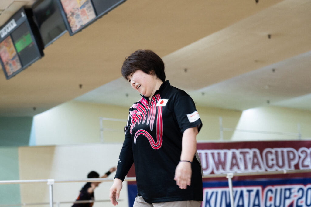 濃いピンクの模様が入った黒っぽいユニフォームを着た尾形さん。左胸には日の丸のマークがついている。