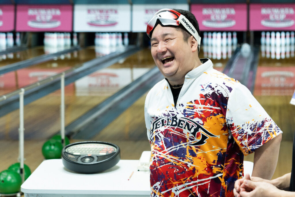 レーンを背に、左手を腰のあたりに当てて満面の笑みで話す井上直也さん。